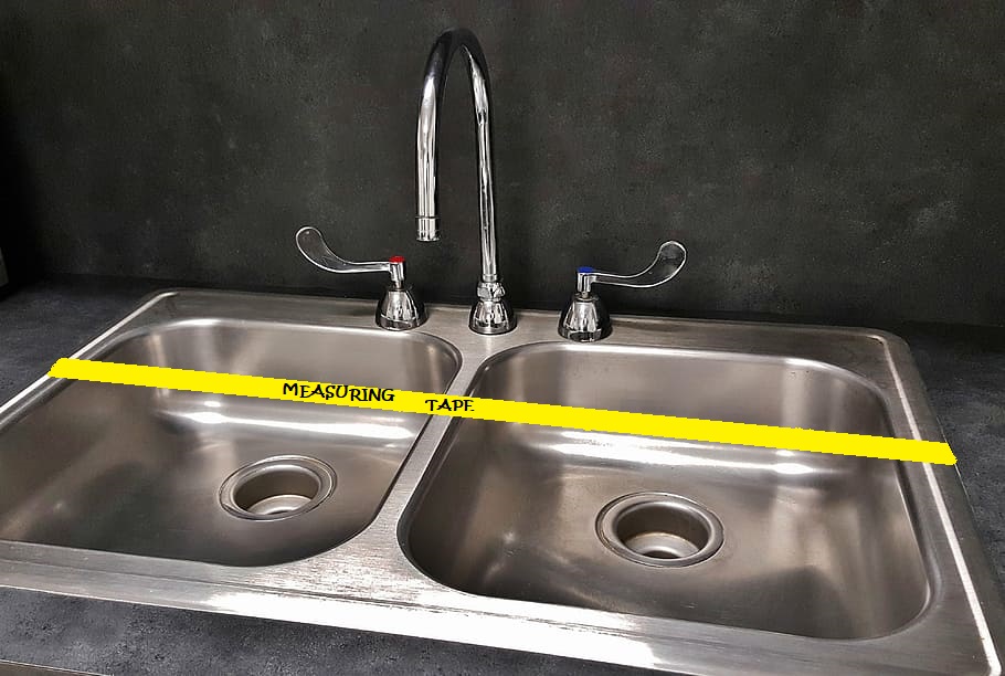 Drain sink with taps and yellow measuring tape