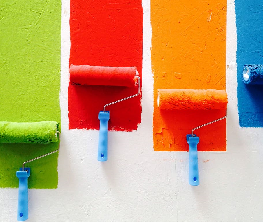 Painting Green, Red, Orange, and Blue paint on a wall with paint rollers