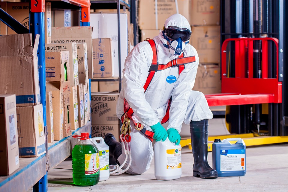 A pest control professional in protective suit opening chemicals
