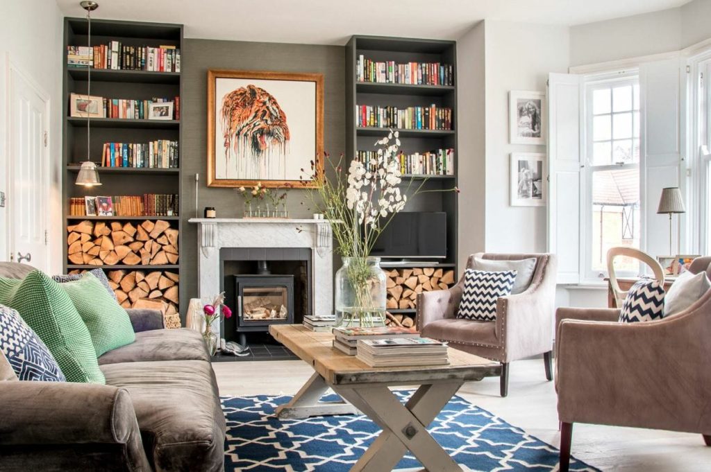A fully decorated living room with sofa, table, books and fire place